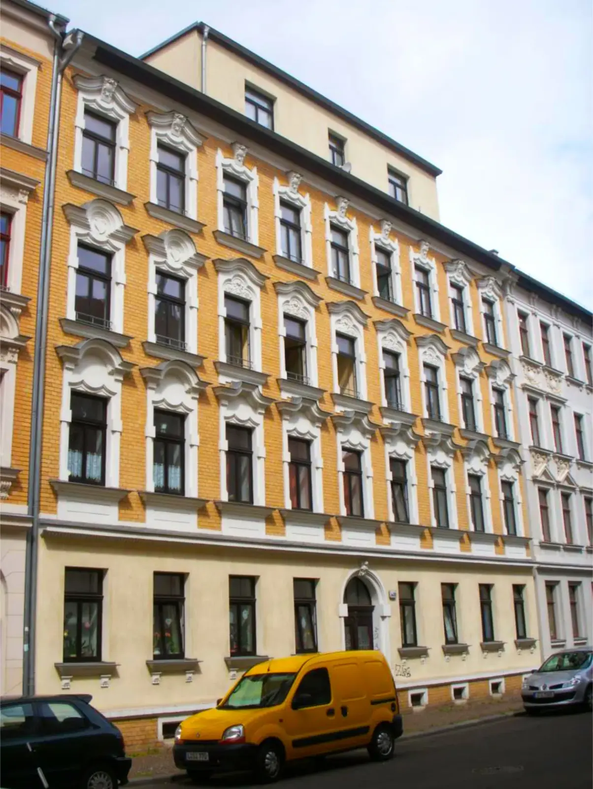 schönes altes Zinshaus in Leipzig, gelbes Mauerwerk mit weißer Verzierung um die dunklen Fenster