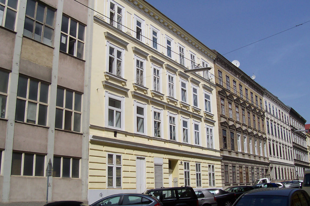 15. Bezirk von Wien, Zinshaus mit gelber Fassade und weißen Fenstern, in aneinandergereihten Häusern