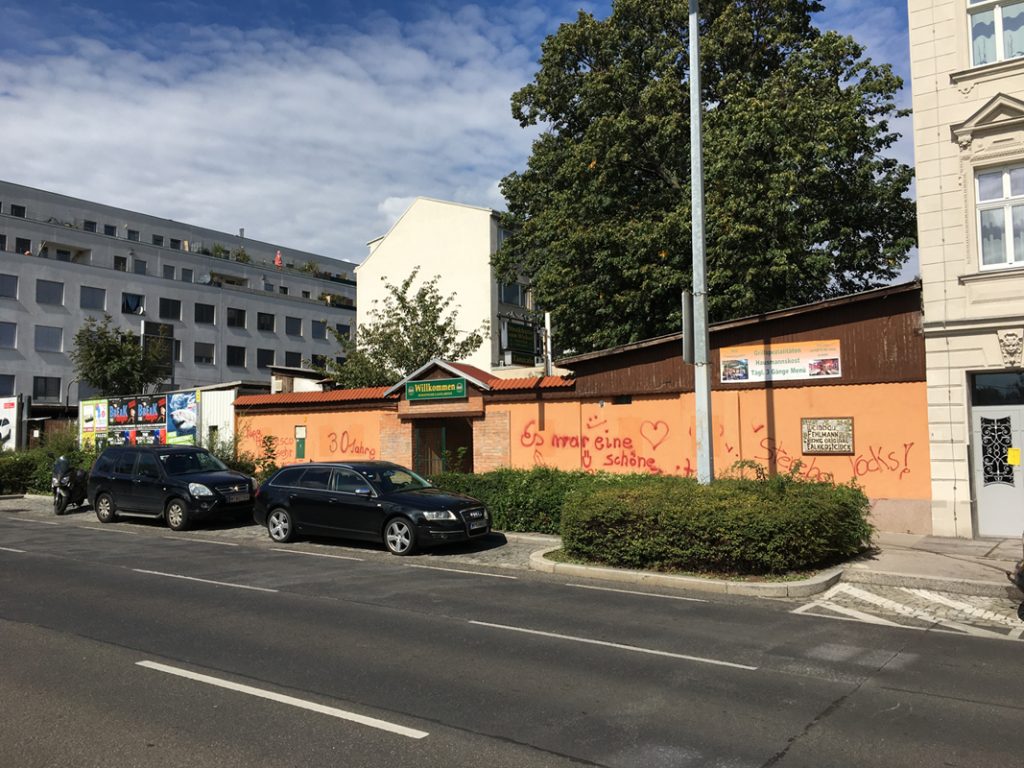 Grundstück mit Gewerbeobjekt im 16. Bezirk Wiens, großer Baum im Hintergrund, rechts davon Zinshaus