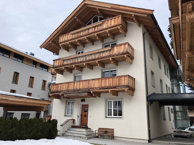 mehrstöckiges Wohngebäude mit Holzbalkonen und heller Fassade in Kitzbühel