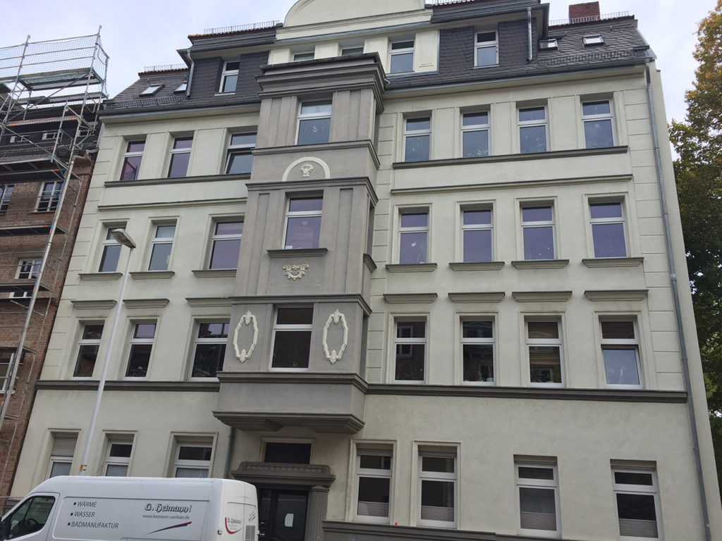 Zinshaus in Chemnitz, graue Fassade mit Erker in der Mitte über dem Hauseingang, graue Fassade