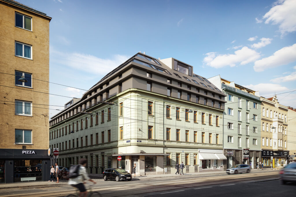 Eckzinshaus im 21. Bezirk von Wien, mintgrüne Fassade, braune Fenster, Geschäftslokal im Erdgeschoss