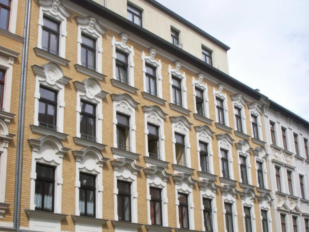 schönes Zinshaus in Leipzig, dunkelbraune Fenster, weiße Verzierungen, Fassade in heller Ziegeloptik