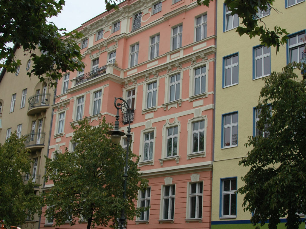 Zinshaus in Berlin, mehrstöckig, rosa Fassade mit weißen Fenstern und Verzierung