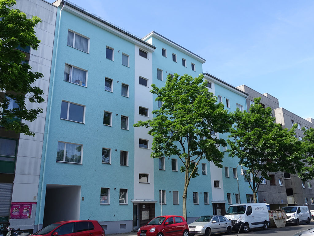 Wohnhaus in Berlin, blaue Fassade, Laubbäume im Vordergrund