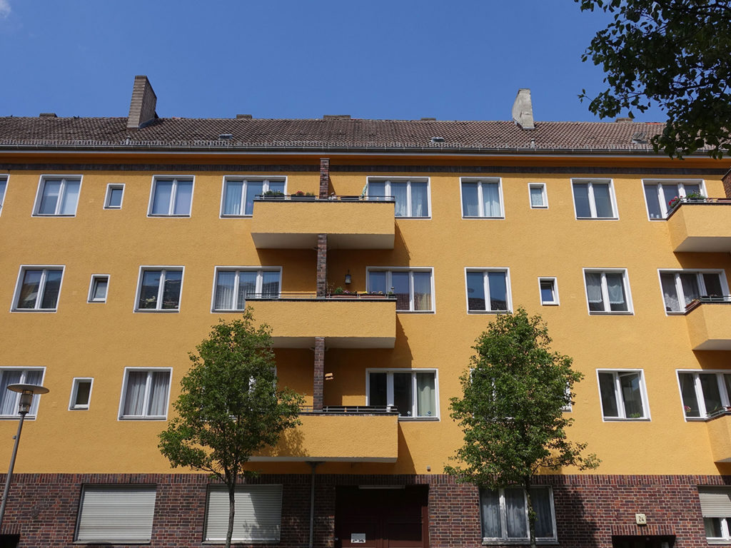 dreistöckige Wohnhausanlage in Berlin, orange Fassade, weiße Fenster, Balkone
