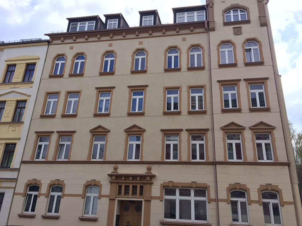 Eckzinshaus, mehrstöckig, in Chemnitz, hellbraune Fassade, mit dunkler Verzierung um den weißen Fenstern