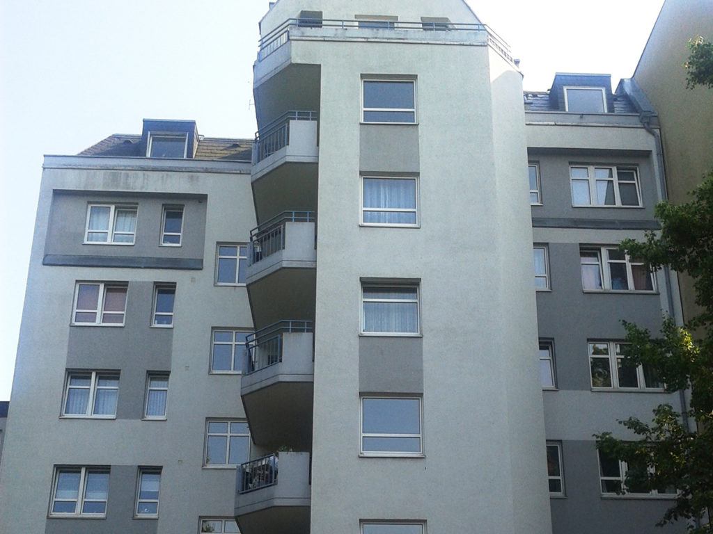 modernes Wohnhaus, mehrstöckig, in Berlin, graue Fassade, Balkone links