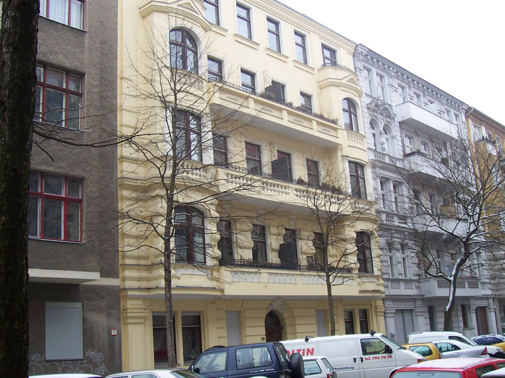 schönes altes Zinshaus in Berlin, hellgelbe Fassade, dunkelbraunen Fenstern und Balkonen