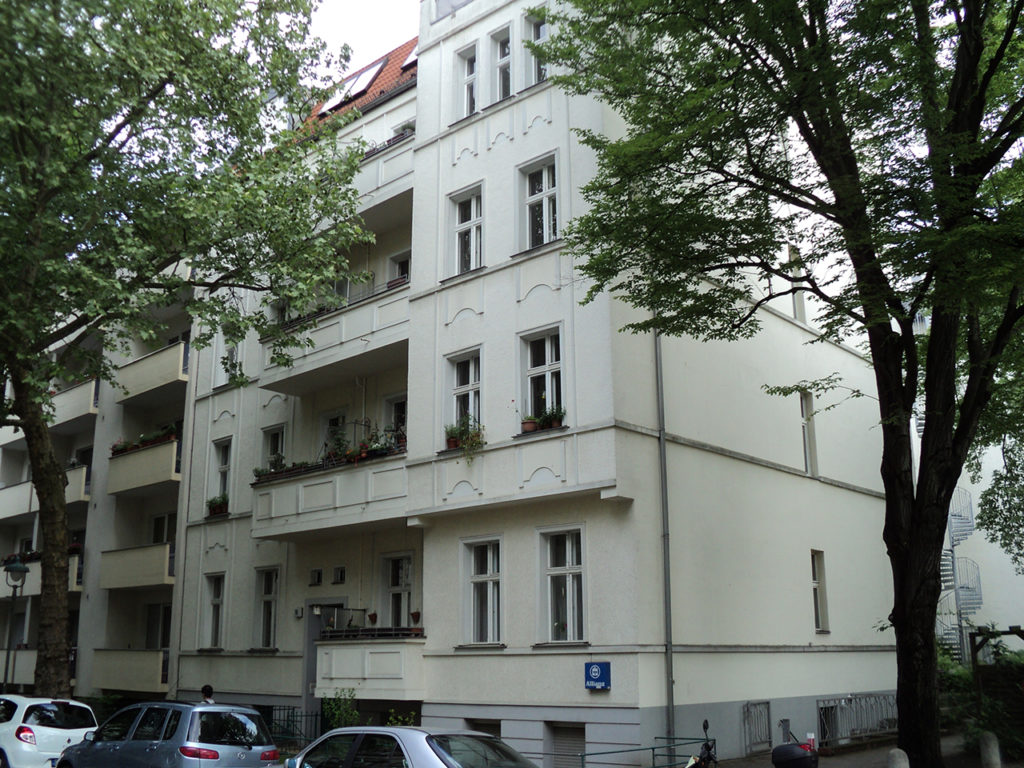 Zinshaus in Berlin, helle Fassade und Fenster, mit Balkonen und Bäumen