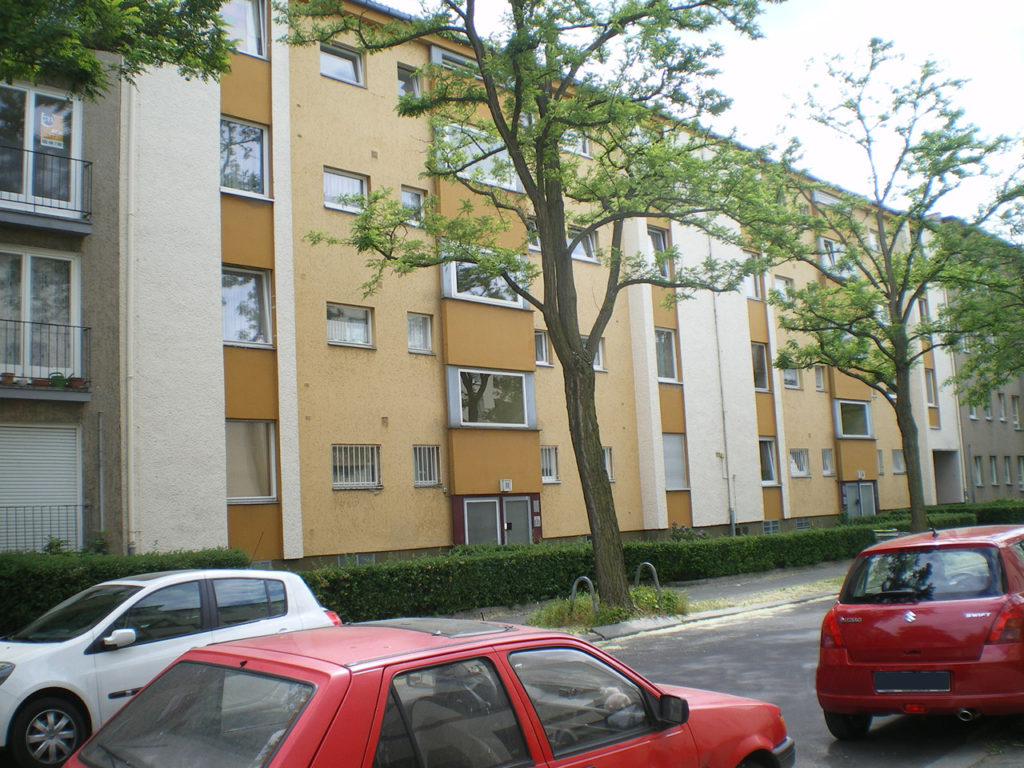 Wohnhausanlage in Berlin, orange Fassade, Laubbäume davor