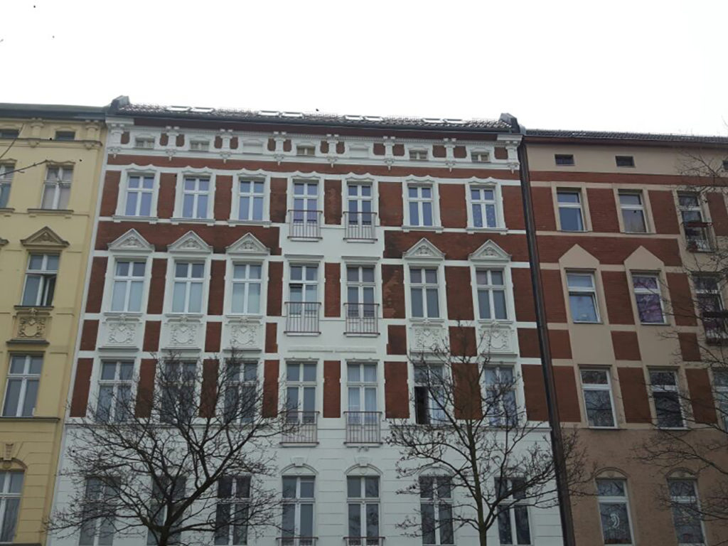 großes Zinshaus in Berlin, helle Fassade mit braunen Elementen und weißen Fenstern