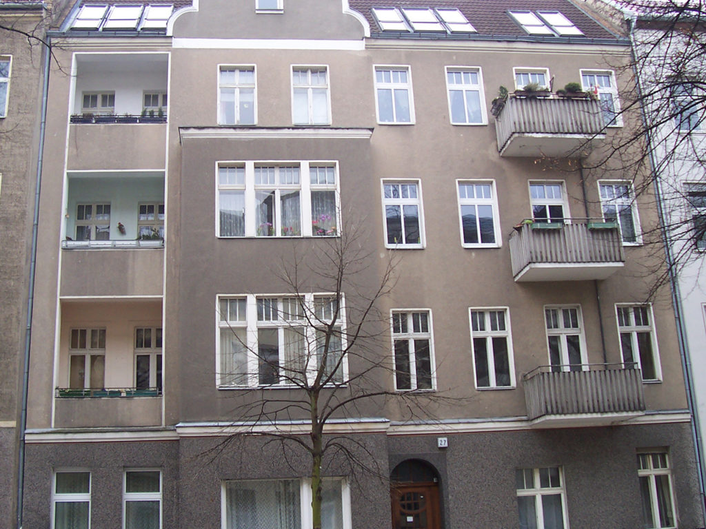 mehrstöckiges Wohnhaus in Berlin, dunkelgraue Fassade, weiße Fenster