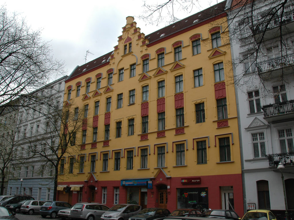 schönes altes Wohnhaus in Berlin, gelb/rote Fassade, dunkle Fenster