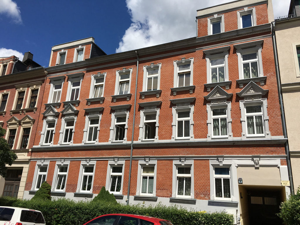 Zinshaus in Chemnitz, Fassade in roter Ziegeloptik, weiße Fenster, Vorgarten