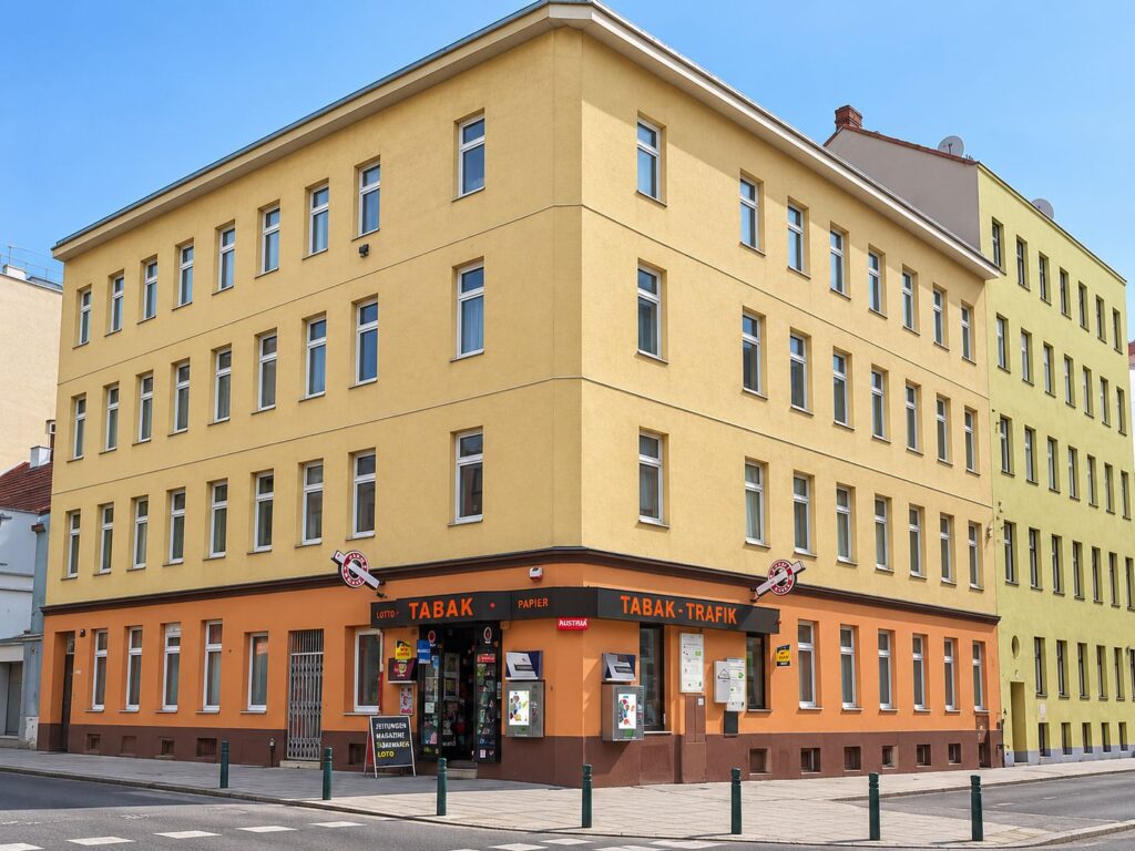 Eckzinshaus mit gelber Fassade, Trafik im Erdgeschoß mit oranger Fassade