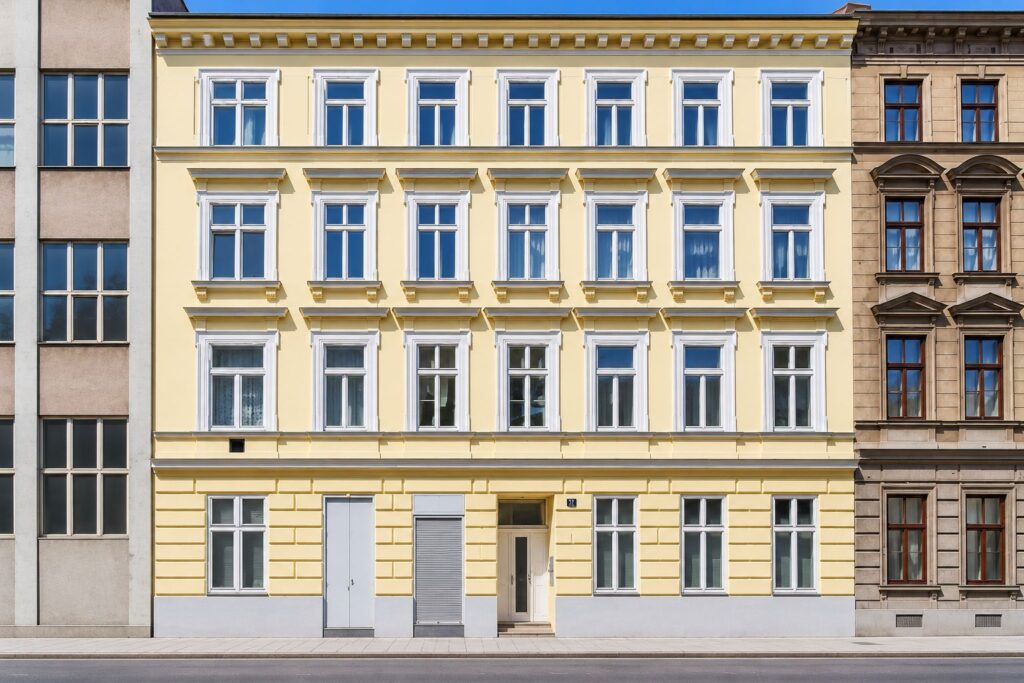 Zinshaus mit gelber Fassade und weißen Fenstern