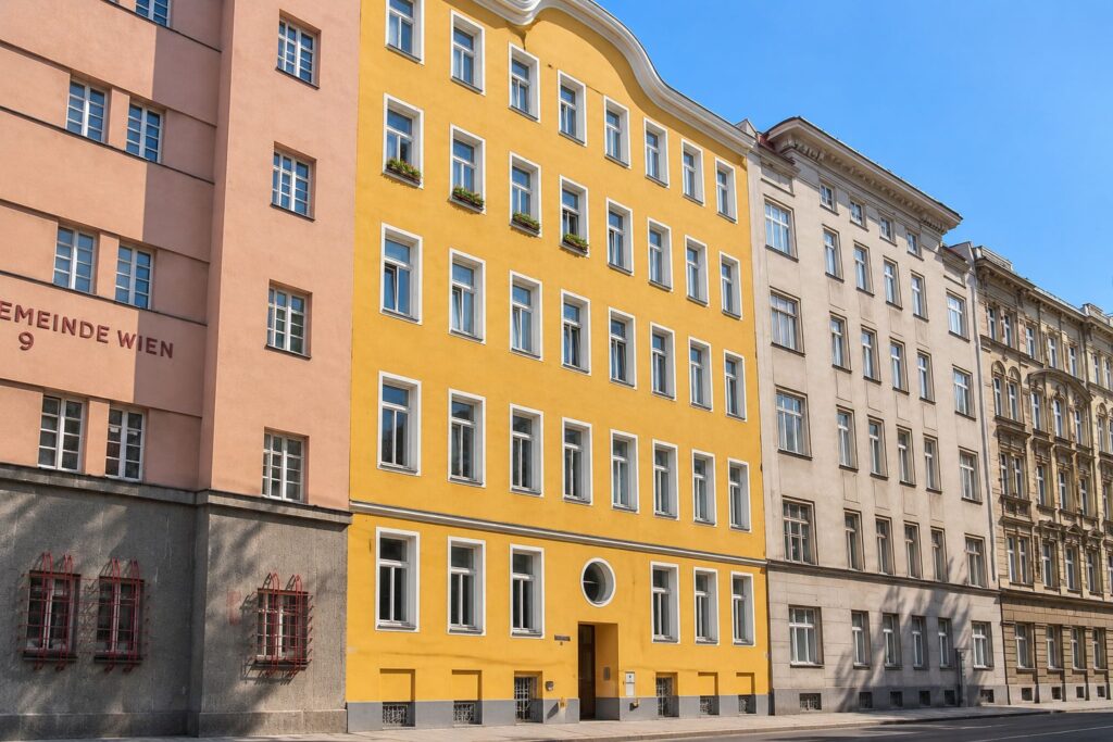 Zinshaus mit oranger Fassade und weißen Fenstern, rundes Fenster über dem Eingangstor