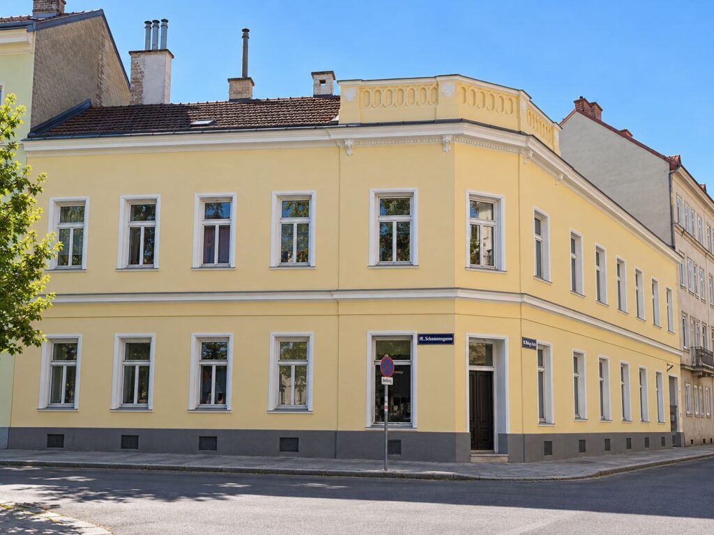 gelbes Eckzinshaus mit weißen Fenstern