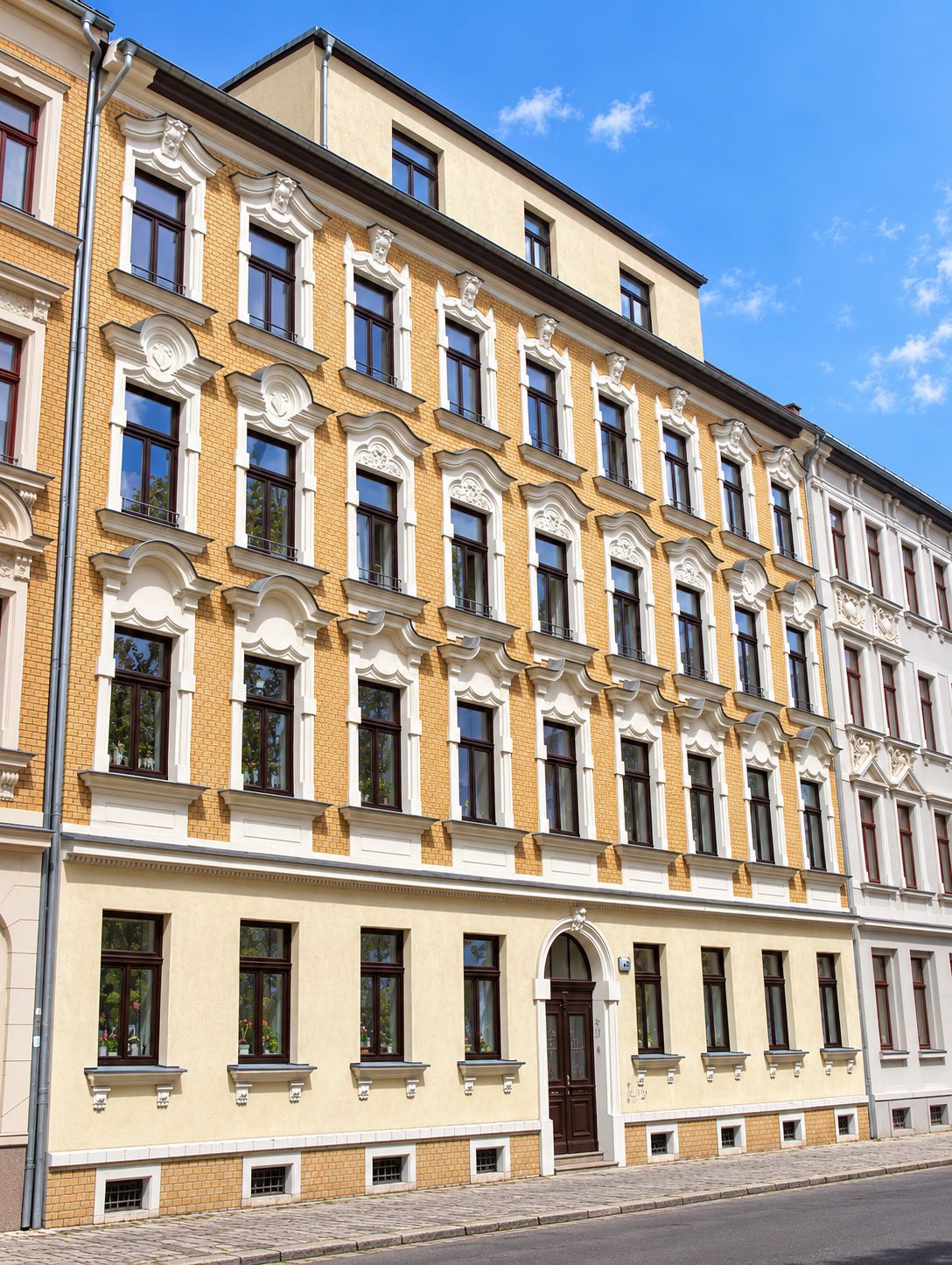 Zinshaus mit gelber Fassade, Fenster weiß umrandet, Fenster braun