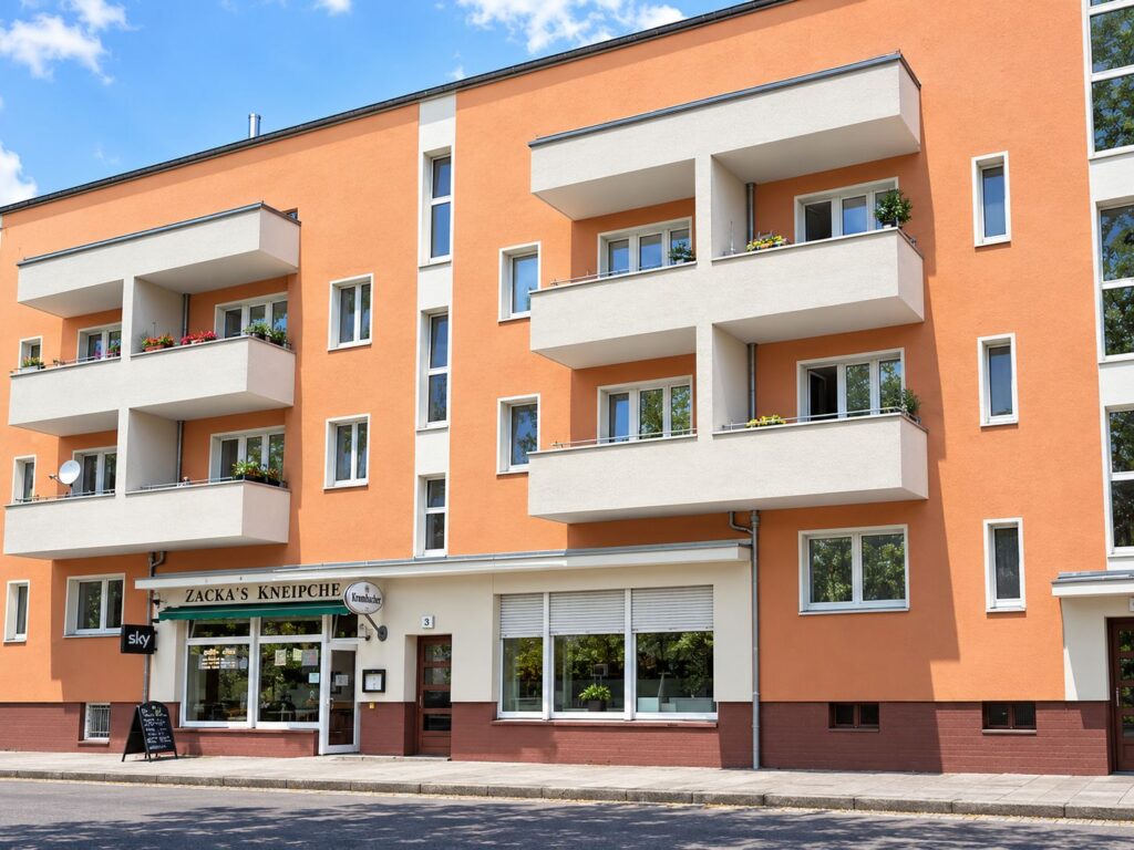 Zinshaus mit oranger Fassade, Balkone und Fenster weiß