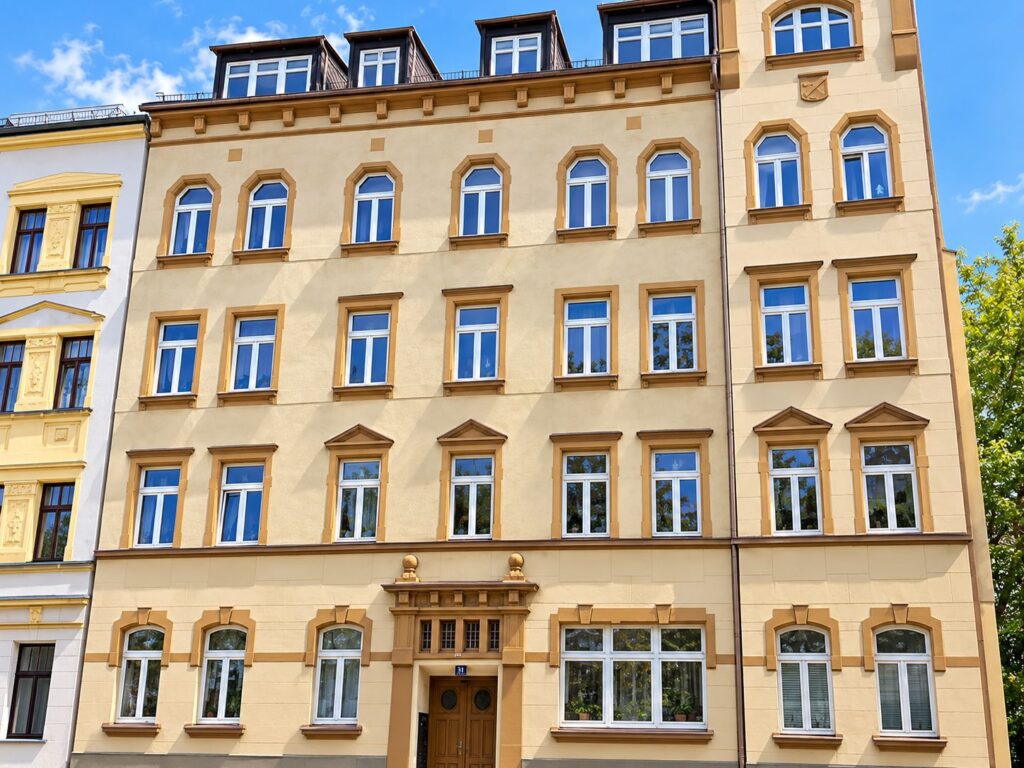Zinshaus mit gelber Fassade, weiße Fenster, Dachgauben