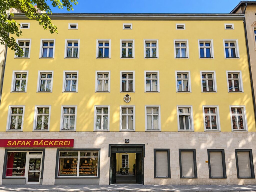 Zinshaus mit gelber Fassade und weißen Fenster, Bäckerei im Erdgeschoß
