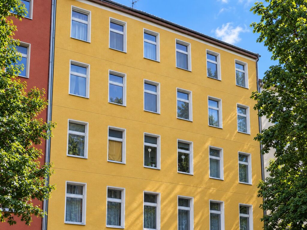 Zinshaus mit dunkelgelber Fassade, weiße Fenster